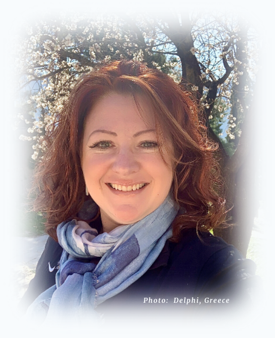 Janine Pratt smiling outdoors among flowering trees